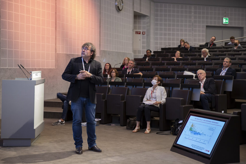 Nicola Marzari giving a presentation in an auditorium with the audience in the background