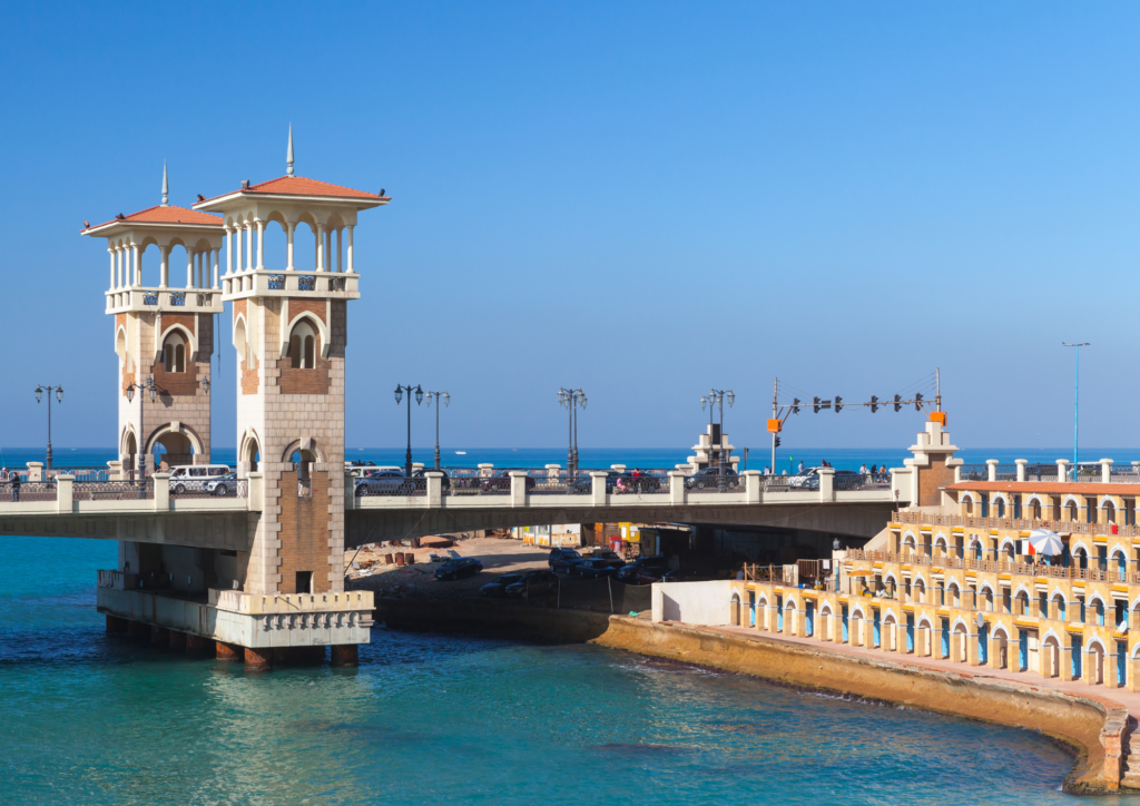 A photo of a bridge with slender watchtowers with tiled roofs in the city of Alexandria, Egypt