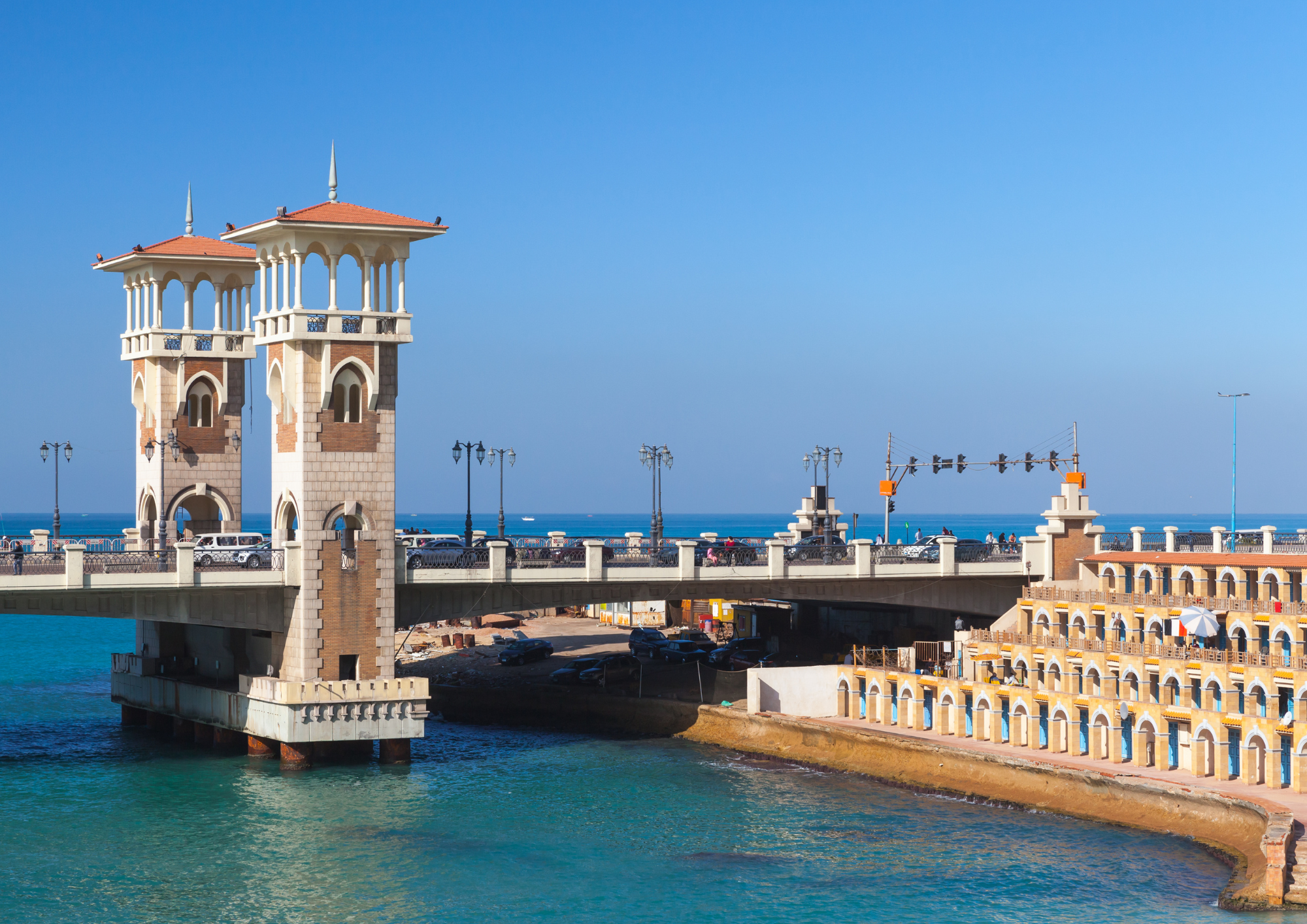 A photo of a bridge with slender watchtowers with tiled roofs in the city of Alexandria, Egypt