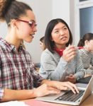 Two females in front of a laptop attending an online training event